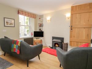a living room with two chairs and a fireplace at 2 Kings Yard in Sedbergh