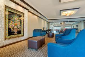 a lobby with blue chairs and a painting on the wall at Comfort Suites Alexandria in Alexandria