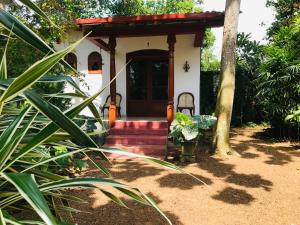 uma pequena casa branca com uma escada vermelha em frente em Swarnapaya résidence em Bentota