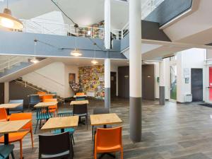 a cafeteria with tables and chairs in a building at Hotel F1 Maurepas in Maurepas