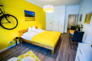 a yellow bedroom with a bed and a bicycle on the wall at Studio 13 "Rapsfeld" in Grömitz