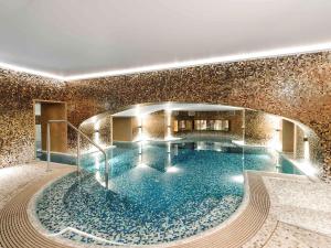 a large swimming pool in a building with a tile wall at Raffles Europejski Warsaw in Warsaw