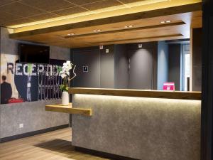 a lobby with a counter with a vase of flowers at Ibis Budget Bourgoin Jallieu Centre in Bourgoin