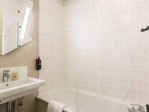 a white bathroom with a tub and a sink at Ibis Budget Bourgoin Jallieu Centre in Bourgoin +17 photos