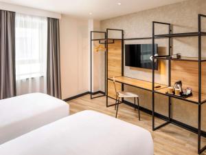 a hotel room with two beds and a desk at ibis London Sutton Point in Sutton