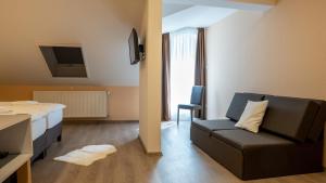 a room with a bed and a couch and a tv at Budapest Airport Eprespark Hotel in Vecsés