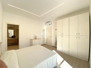 a white bedroom with a bed and a dresser at residence cristallo in Alassio