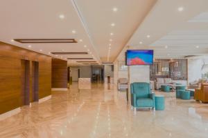 a lobby with chairs and a tv on the ceiling at Ananth The Grand in Hubli