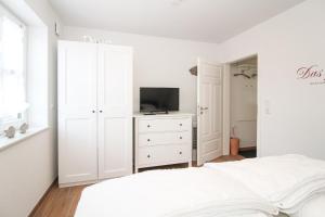 ein weißes Schlafzimmer mit einem Bett und einem TV in der Unterkunft Ferienwohnung Zeit zu Zweit Greetsiel in Greetsiel