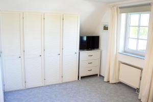 a bedroom with white closets and a flat screen tv at Haus Birnbaum in Zingst