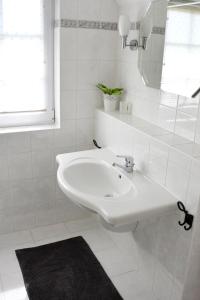 a white bathroom with a sink and a mirror at Haus Birnbaum in Zingst