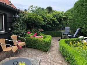 a garden with chairs and a table and flowers at Huize Oostduin in Oostkapelle
