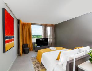 a hotel room with a bed and a television at Noom Hotel Abidjan Plateau in Abidjan