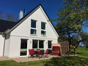 a white house with red chairs and a table at Ferienhaus Sommersonne, Hof zur Sonnenseite Fehmarn, 4 Sterne in Fehmarn