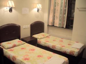 2 Einzelbetten in einem Zimmer mit Blumen darauf in der Unterkunft C U Again Hostel in Hongkong