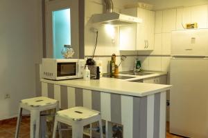 a kitchen with a white refrigerator and a counter with stools at Apartamento Ene one in Cartagena