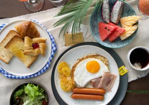 a table with two plates of food with eggs and toast at Naithonburi Beach Resort - SHA Extra Plus in Nai Thon Beach