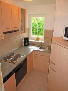 a kitchen with a stove and a sink and a window at "Landhaus Voss" Typ 3 Nr9 in Staberdorf