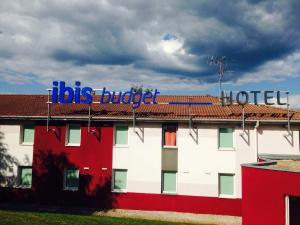 a red and white building with a blue sign on it at ibis budget Besançon Ecole Valentin in Besançon