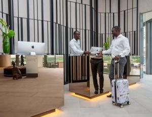 Due uomini sono in piedi in una hall con una valigia di Noom Hotel Abidjan Plateau a Abidjan