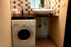 a bathroom with a sink and a washing machine at Mango Apartment @ Palolem Garden Estate in Canacona