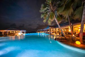 a pool at night with palm trees and buildings at La Toubana Hotel & Spa in Sainte-Anne