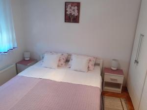 Schlafzimmer mit einem Bett mit rosa und weißen Kissen in der Unterkunft Apartman Mario in Osijek