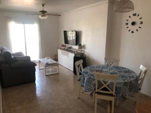 sala de estar con mesa, sofá y cocina en Agua marina en Playas de Orihuela