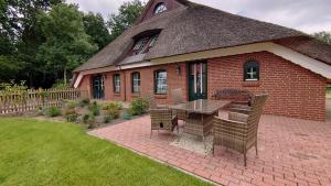 a brick house with a table and chairs in a yard at De Tuun - Landhaus Lübbertsfehn in Ihlow