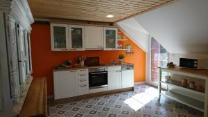 a kitchen with white cabinets and an orange wall at De Tuun - Landhaus Lübbertsfehn in Ihlow