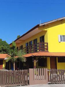 a yellow house with a fence in front of it at Pousada Toca Do Raul in Itapoa