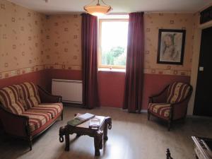- un salon avec deux chaises, une table et une fenêtre dans l'établissement Chambres d'hôtes de la Becterie, à Quettetot