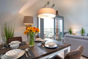 a dining room with a table with flowers and a couch at Ostsee - Appartement Nr 52 "Seglerlounge" im Strand Resort in Heiligenhafen