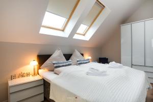 ハイリゲンハーフェンにあるOstsee - Appartement Nr 52 "Seglerlounge" im Strand Resortのベッドルーム(天窓付きの大きな白いベッド1台付)