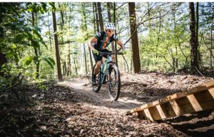 a man riding a bike on a trail in the woods at Bosboerderij de Veluwe, luxe huisje in het bos in Lunteren