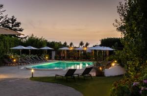 a swimming pool with chairs and umbrellas at night at Boutique Hotel Casa Mariantonia in Anacapri