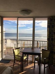 een kamer met een tafel en stoelen en uitzicht op de oceaan bij Cove Motel Oceanfront in Daytona Beach