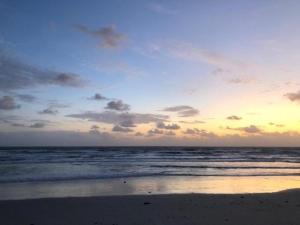 una puesta de sol en una playa con el océano en Cove Motel Oceanfront en Daytona Beach