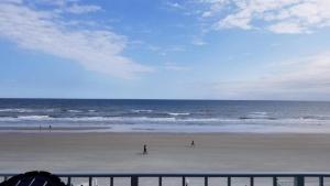 two people walking on the beach near the ocean at Cove Motel Oceanfront in Daytona Beach