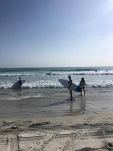 un groupe de personnes se promenant sur la plage avec des planches de surf dans l'établissement Cove Motel Oceanfront, à Daytona Beach