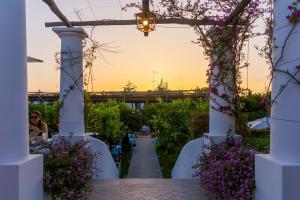 an arbor with white chairs and purple flowers at Boutique Hotel Casa Mariantonia in Anacapri