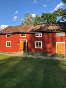 una casa roja con un césped verde delante de ella en Albäck Gård Bagarstugan - Granne med Sala Golfklubb, en Sala