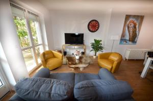 ein Wohnzimmer mit einem Sofa, Stühlen und einem Tisch in der Unterkunft Ferienwohnungen Marienthal in Hamburg