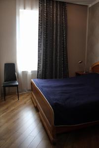 een slaapkamer met een bed, een raam en een stoel bij Ann's Apartment in Tbilisi City