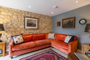 an orange couch in a living room with a stone wall at Little Coach House in Beckley