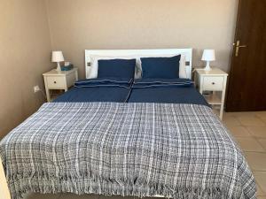 - un lit avec une couverture bleue et blanche et 2 tables de chevet dans l'établissement M & P Apartment - San Marcos, à Icod de los Vinos