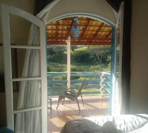 Habitación con puerta abierta y porche con silla en Pousada Vison, en Itapeva