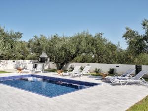 a swimming pool with chairs and a fire place in a yard at Kapodistria Luxury Villas - 3-Bedroom Villas with Private Pool, by ZanteWize in Planos +63 photos