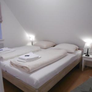 a bed with white sheets and pillows on it at FöhrZeit in Wrixum