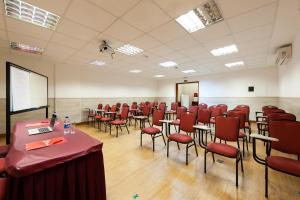 a conference room with red chairs and tables and a screen at Hotel Santorini in Vila Velha +37 photos